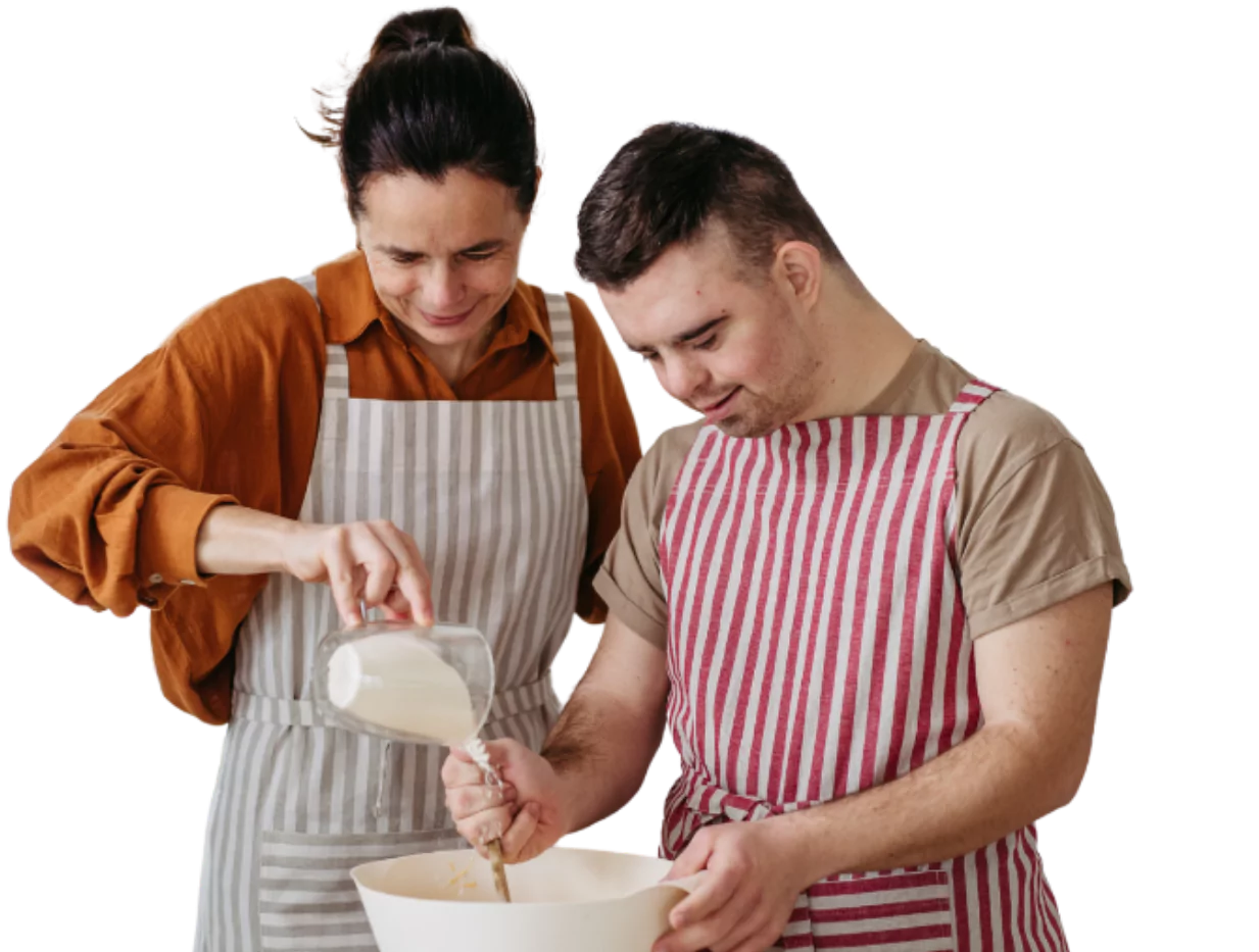 Disabled man with down syndrome baking with support worker in kitchen